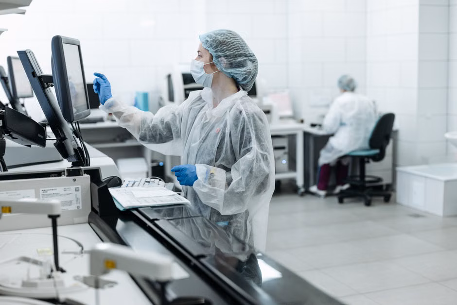 A lab technician wearing PPE works on analysis in a medical laboratory.